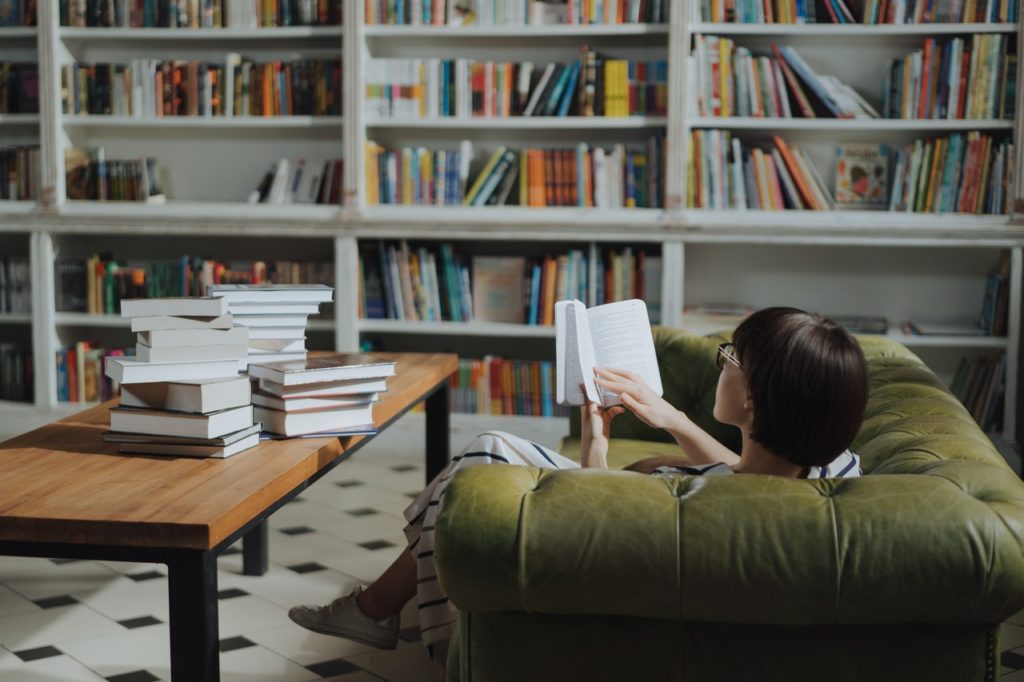 A woman sitting on a sofa reading books.