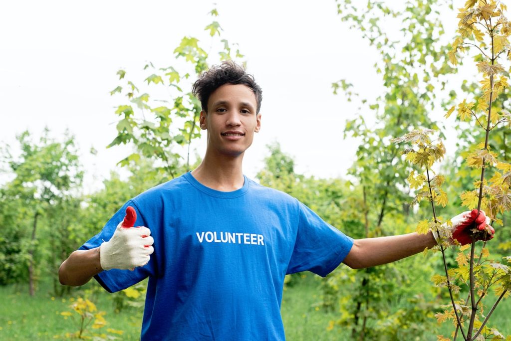 An aspiring architect wearing blue volunteer shirt helping with planting programs for the environment.