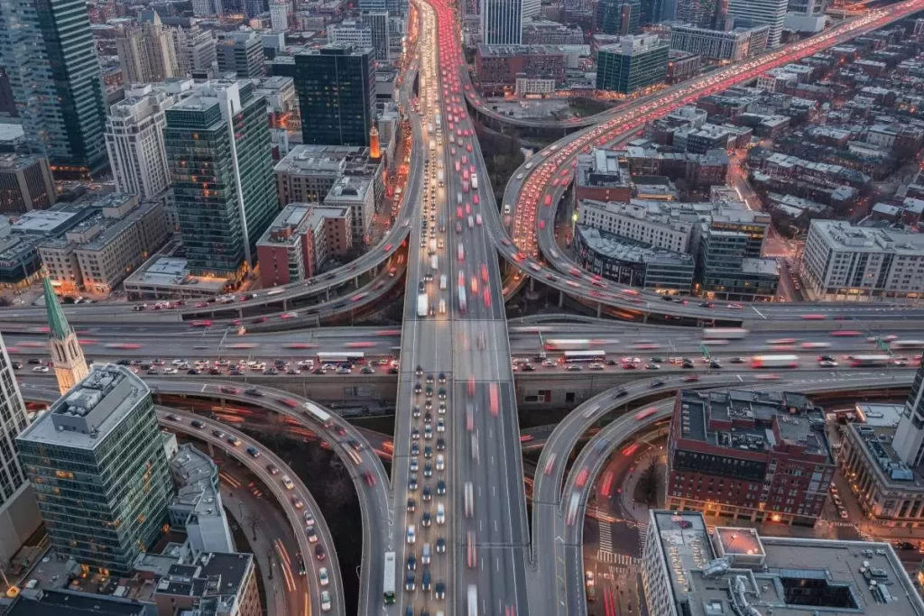 An aerial view of a busy highway interchange in the Philippines with multiple overpasses, looping ramps, merging lanes, and adjacent urban developments, illustrating traffic flow analysis in a Traffic Impact Assessment for real estate development.