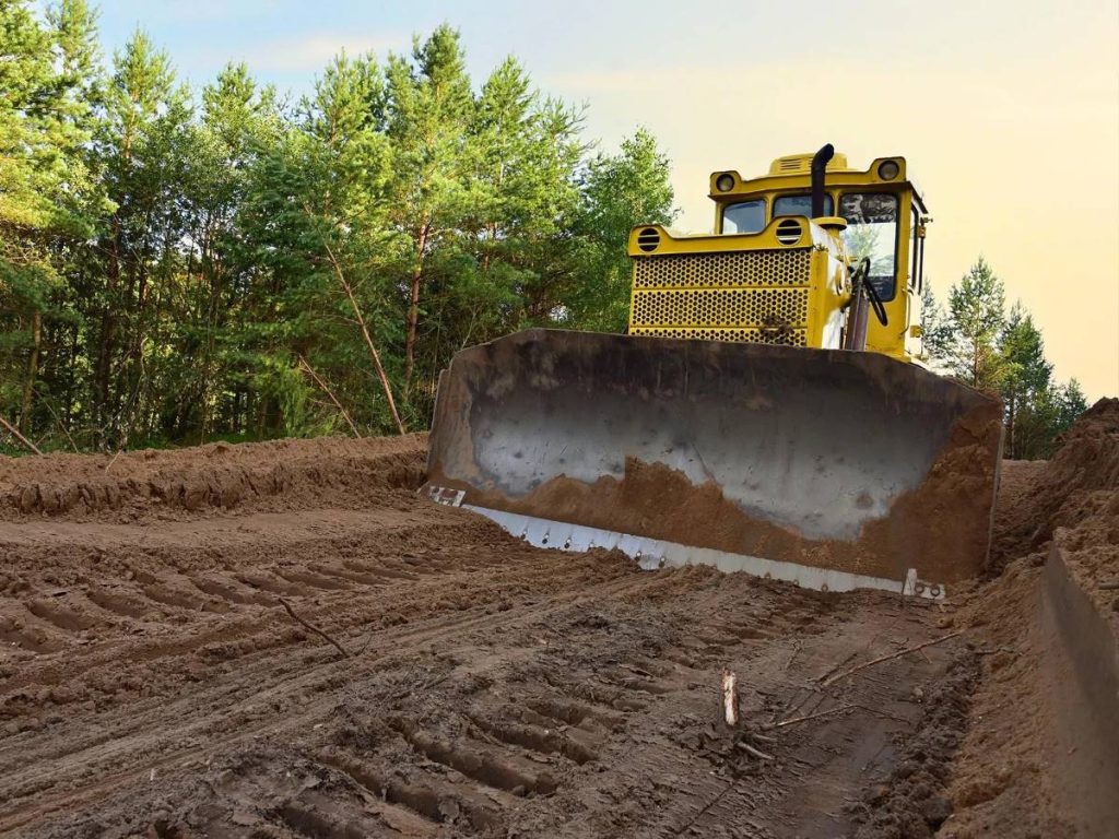 A piece of land undergoing earth grading by a tractor.