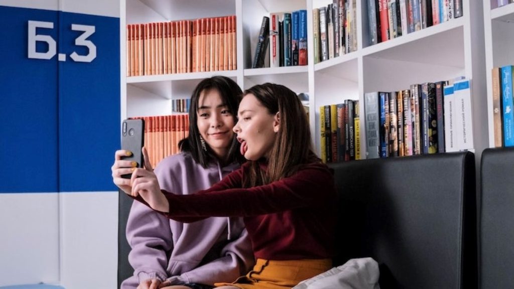 Two girls in a library sharing a selfie moment.
