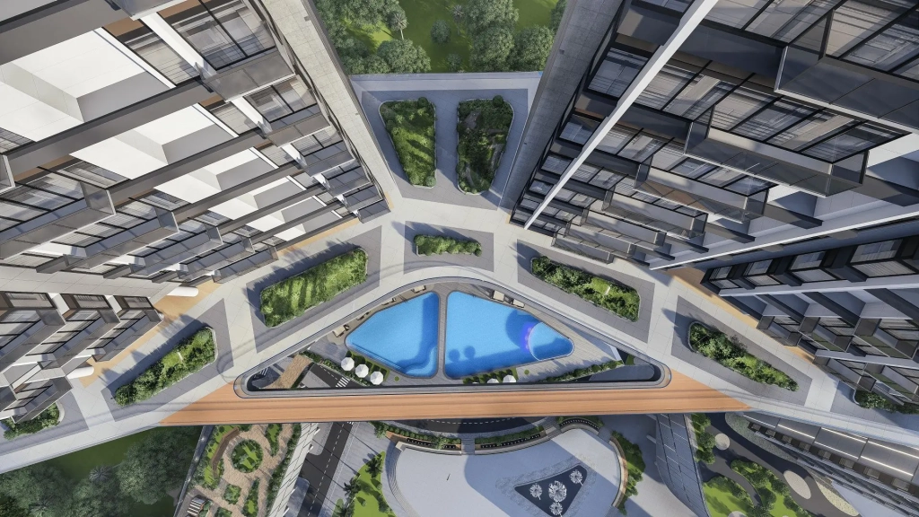 Aerial top view of twin high-rise residential towers connected by sky bridge, featuring triangular-shaped pool deck with two swimming pools, landscaped garden beds, lounge seating areas, linear planter boxes, pedestrian walkways, road access, and surrounding urban greenery.