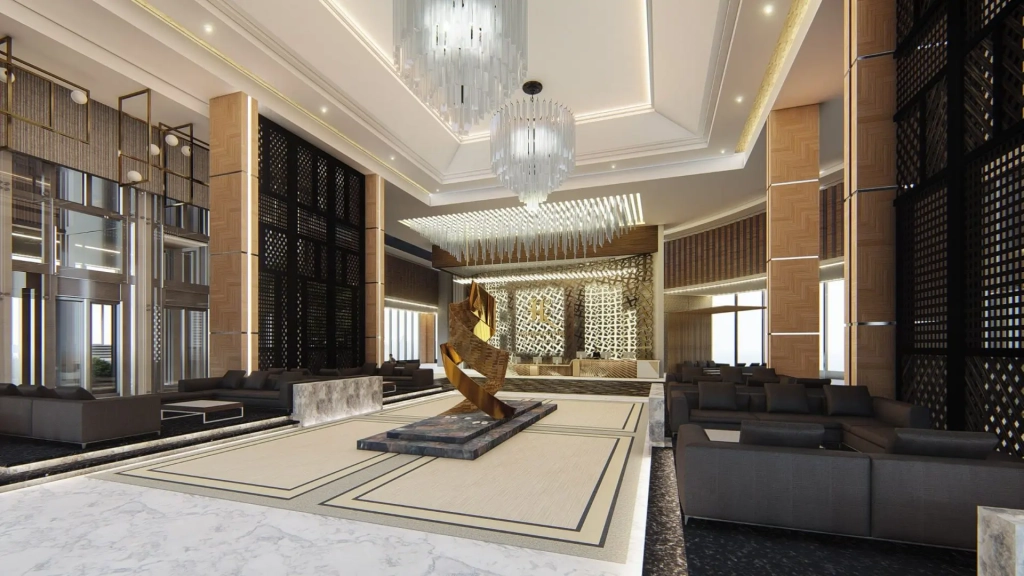 Hotel lobby interior featuring double-height ceilings, modern chandeliers, central sculptural art piece on raised platform, marble flooring, timber-accented columns, dark upholstered lounge seating, decorative wall screens, ambient lighting, and spacious circulation pathways.