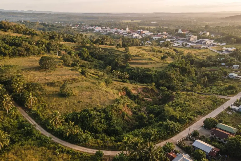 Aerial view of an undeveloped Philippine hillside property showing sloping terrain, natural drainage corridors, and an existing access road.